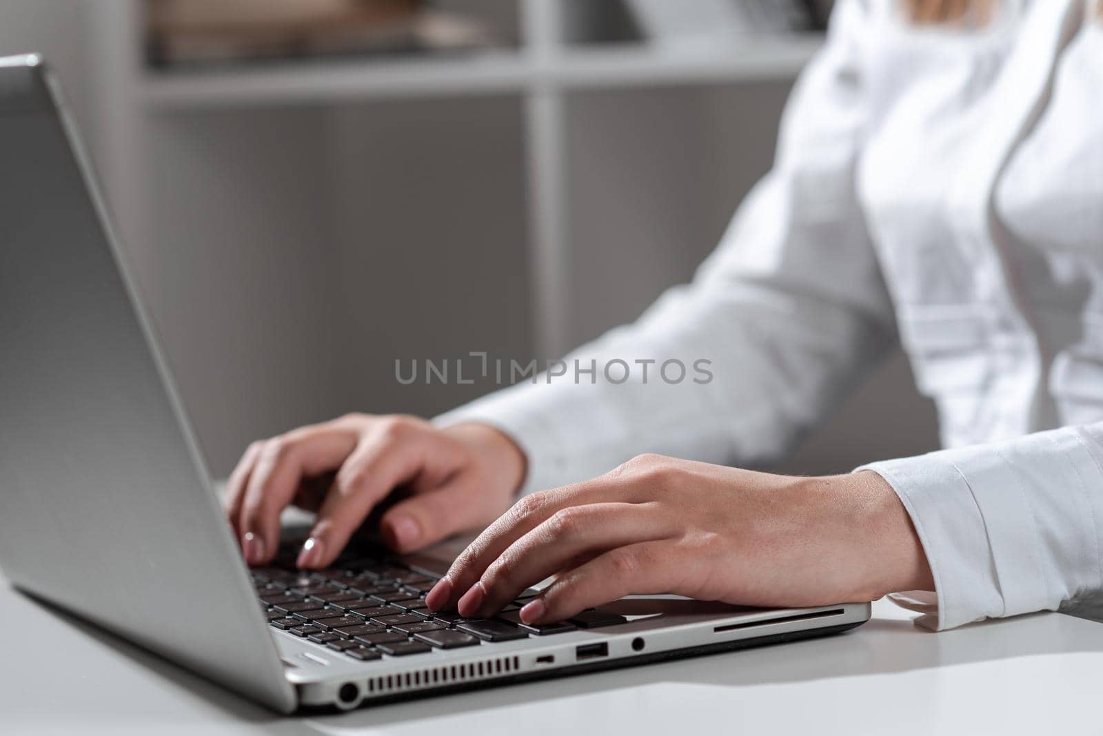 Businesswoman Typing Recent Updates On Lap Top Keyboard On Desk. Woman In Office Writing Important Message On Computer. Executive Inserting Crutial Data Into Pc. by nialowwa