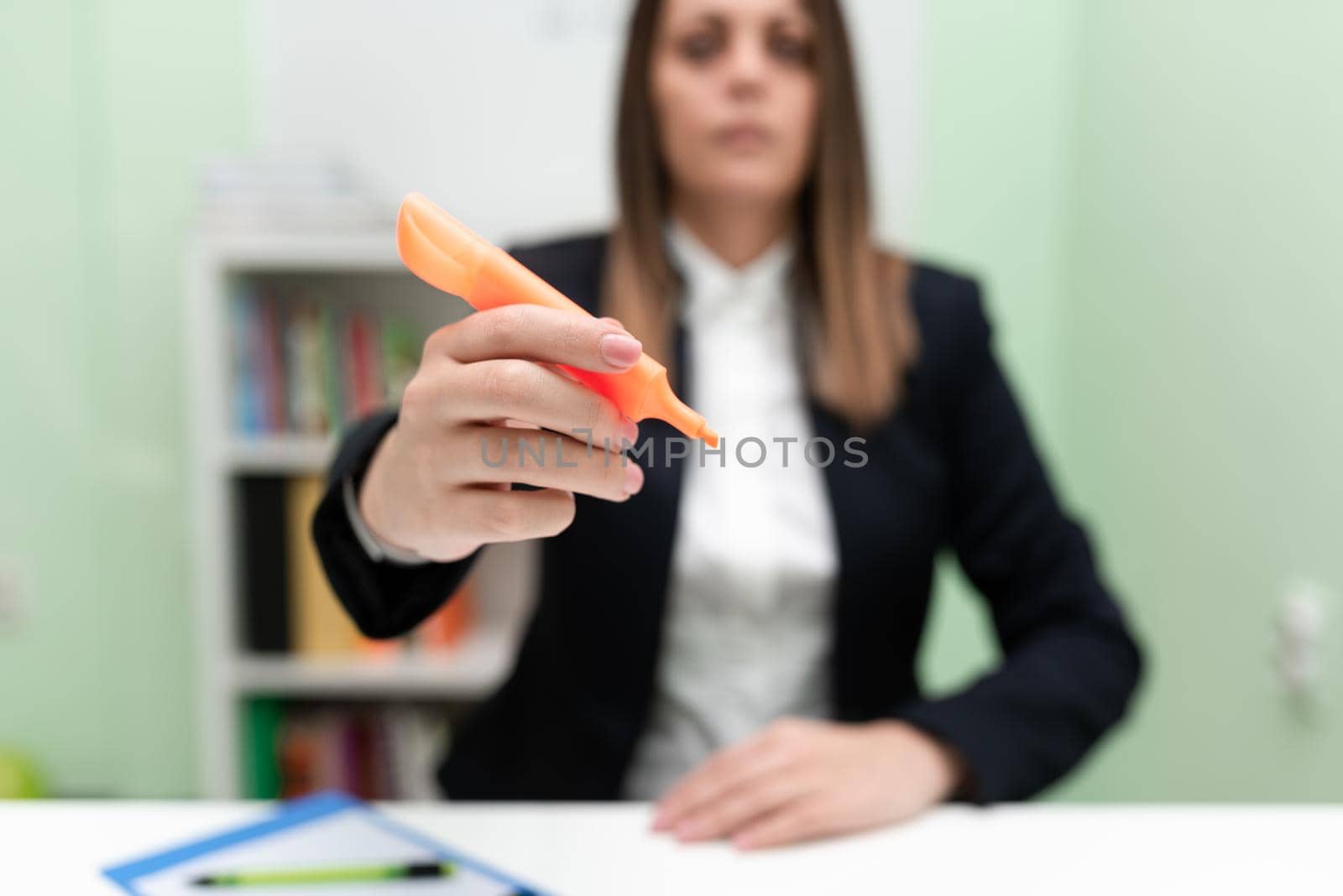 Businesswoman Holding Marker With One Hand And Pointing Important Ideas. Woman With Colored Pen Showing Recent Updates. Executive Displaying Late News. by nialowwa