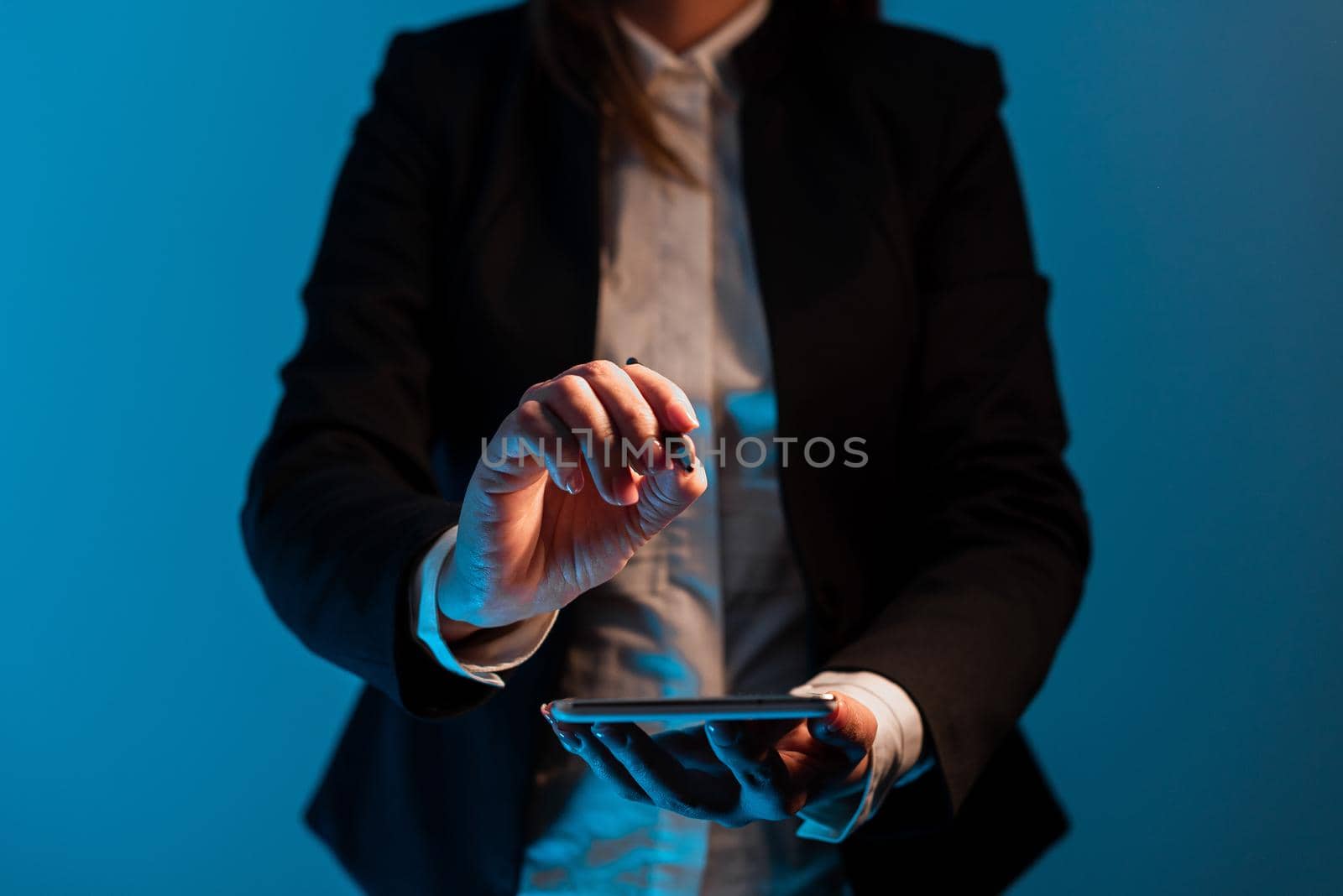 Businesswoman Holding Mobile Phone And Pointing With Pen On Important Messages . Standing Woman In Suit Having Cellphone And Presenting Crutial Informations. by nialowwa