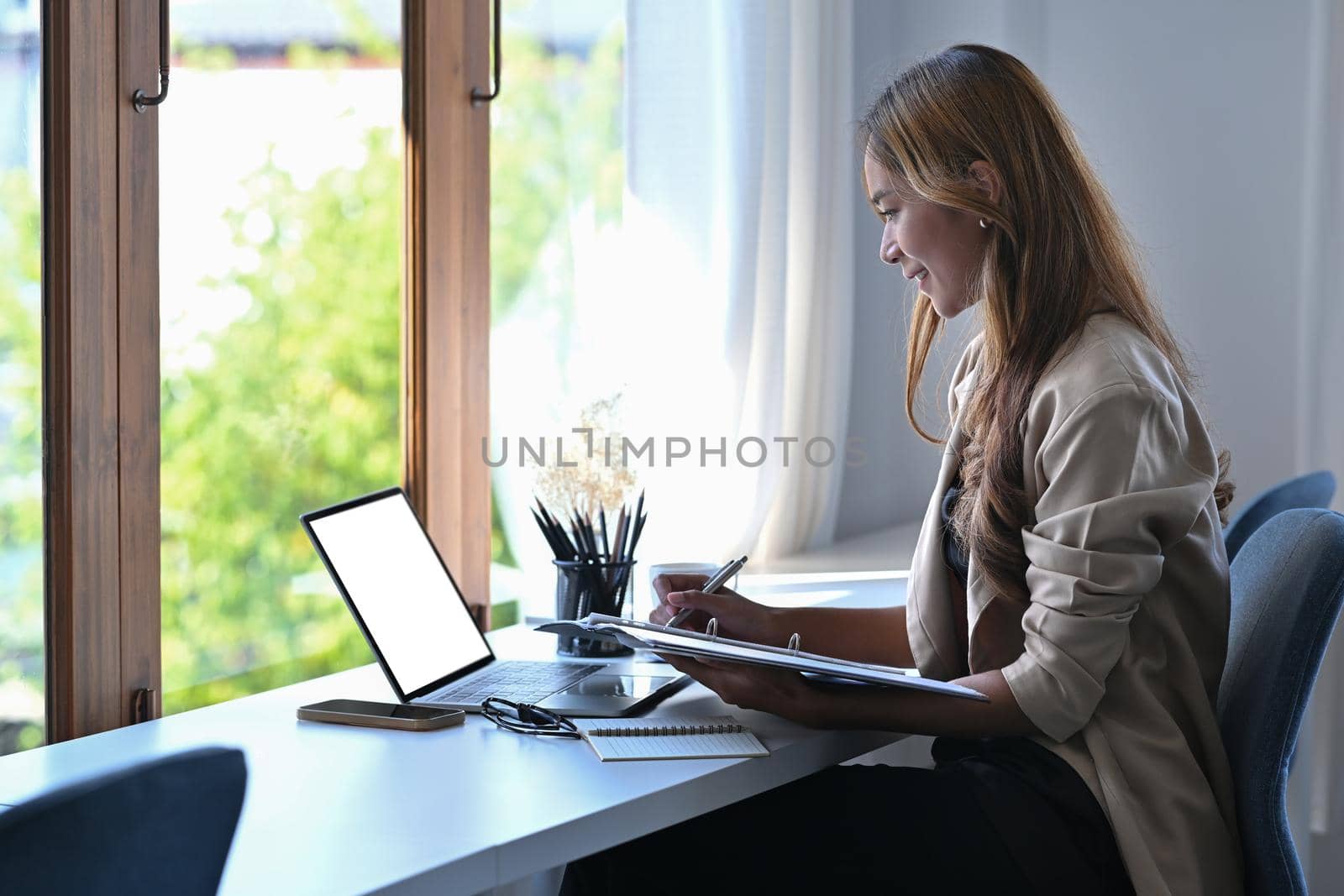 Side view young female entrepreneur working with laptop at her workplace.