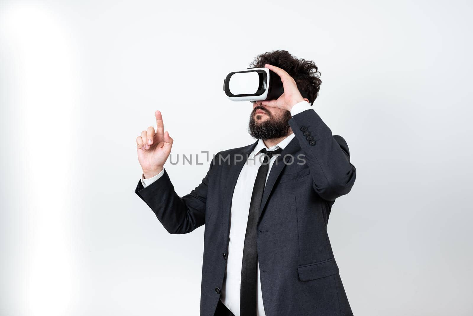 Man Wearing Vr Glasses And Pointing On Important Messages With One Finger. Businessman Having Virtual Reality Eyeglasses And Showing Crutial Informations. by nialowwa