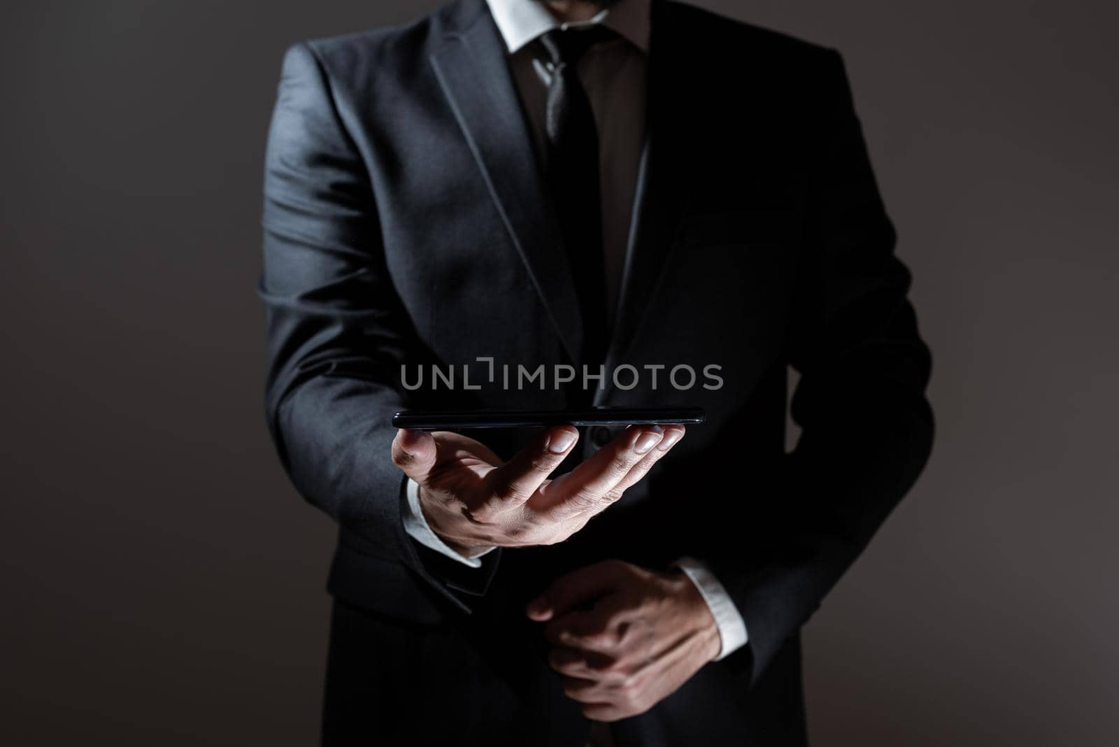 Businessman Holding Tablet With Both Hands And Presenting Important Data. Man In Suit Showing Crutial Information. Executive Displaying Crutial Announcement. by nialowwa