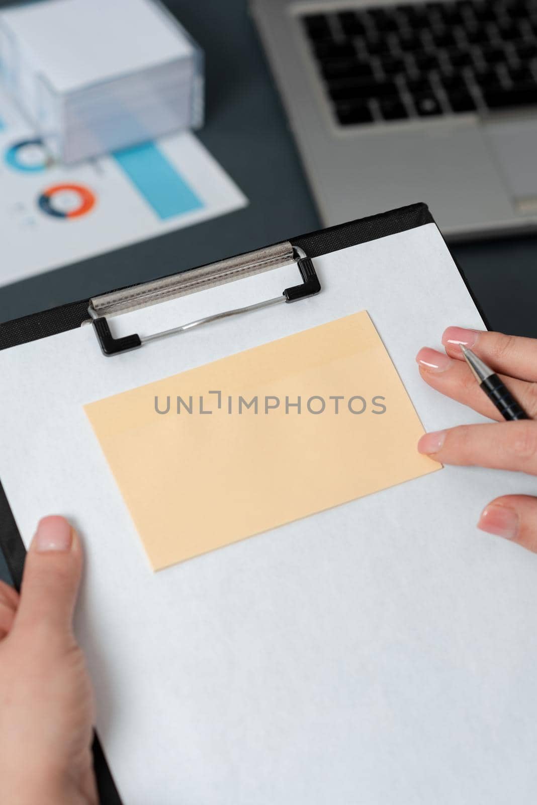 Businesswoman Holding Pen And Clipboard With Note On It With Important Messages. Woman Having Memo With Crutial Information. Executive Showing Critical Data On Paper. by nialowwa