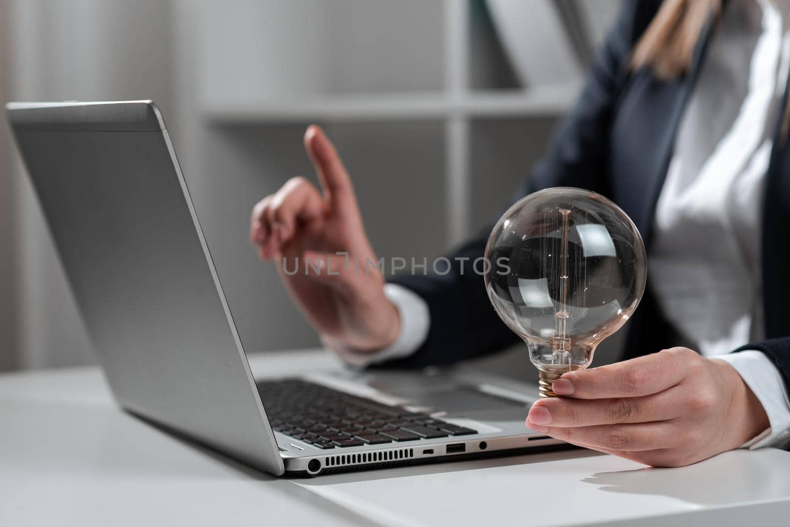 Woman Pointing Recent Updates With One Finger On Desk Holding Lightbulb.