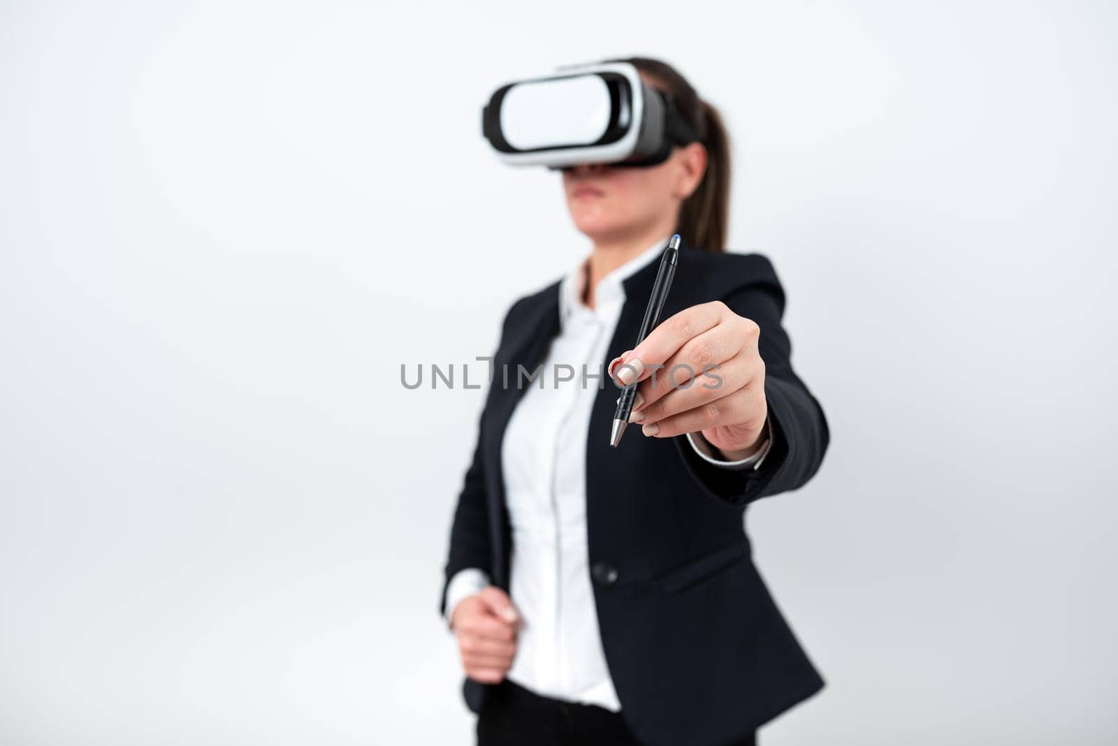 Woman Wearing Vr Glasses And Pointing On Recent Updates With Pen. Businesswoman Having Virtual Reality Eyeglasses And Presenting New Idea. Executive Showing Late Data. by nialowwa