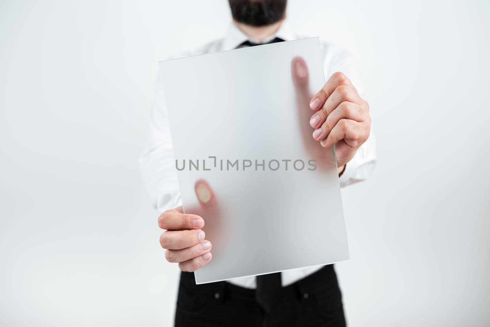 Male Professional Holding Blank Placard And Showing Important Data. Businessman With Paper In Hands Presenting Marketing Strategies For Development Of Business. by nialowwa