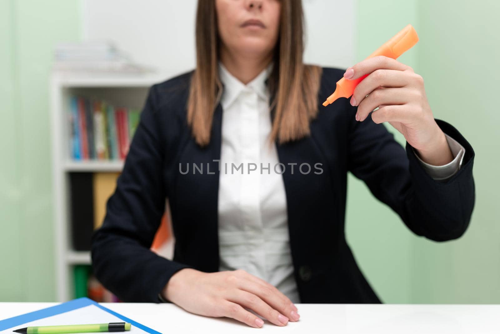 Businesswoman Holding Marker With One Hand And Pointing Important Ideas. Woman With Colored Pen Showing Recent Updates. Executive Displaying Late News. by nialowwa