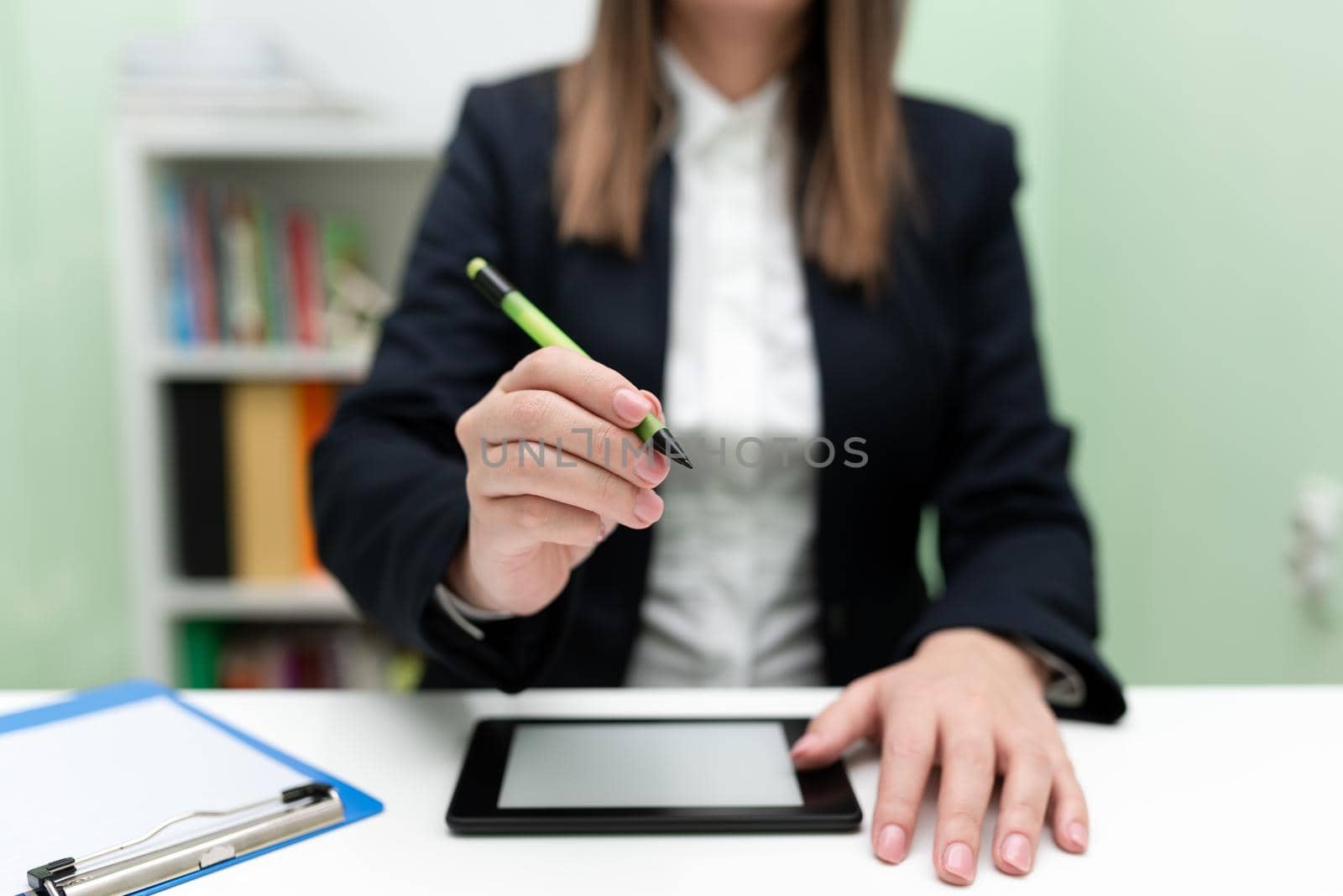 Businesswoman Having Tablet On Desk And Pointing Important Ideas With Pencil. Woman With Phone Showing Recent Updates. Executive Displaying Late News. by nialowwa