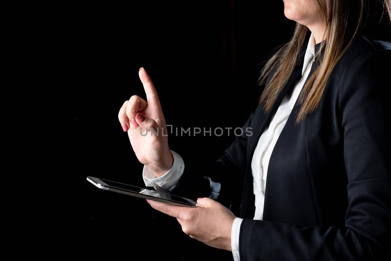 Businesswoman Holding Tablet And Pointing With One Finger On Important Message. Executive In Suit Presenting Crutial Information. Woman Showing Critical Announcement. by nialowwa