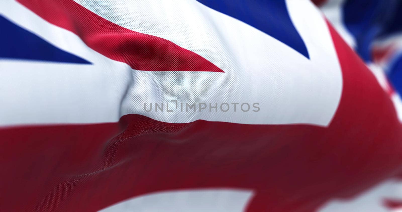 Close-up view of the United Kingdom flag waving in the wind. United Kingdom is a sovereign country that comprises England, Wales, Scotland, and Northern Ireland. Fabric background