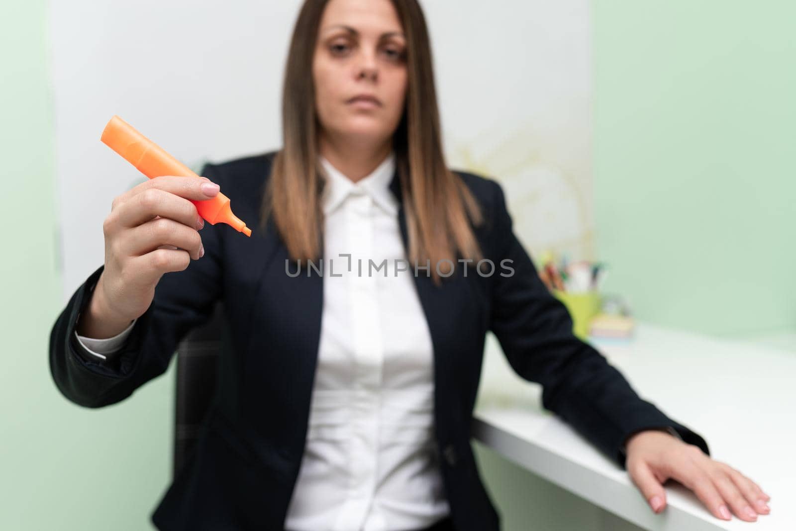 Businesswoman Holding Marker With One Hand And Pointing Important Ideas. Woman With Colored Pen Showing Recent Updates. Executive Displaying Late News. by nialowwa