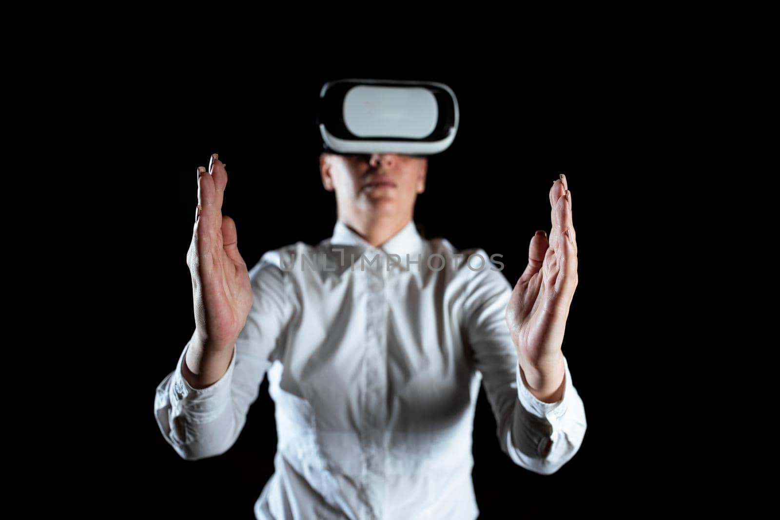 Businesswoman Wearing Virtual Reality Goggles And Enjoying Simulator. Elegant Woman Using Futuristic Gadget Gesturing And Presenting Modern Innovative Technology. by nialowwa