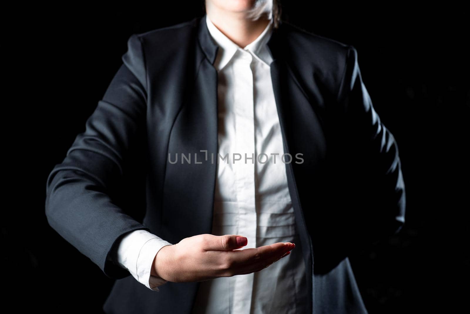 Businesswoman Holding Important Message In One Hand. Woman In Suit Showing New Crutial Idea In A Palm. Executive Presenting Updated Critical Information. by nialowwa