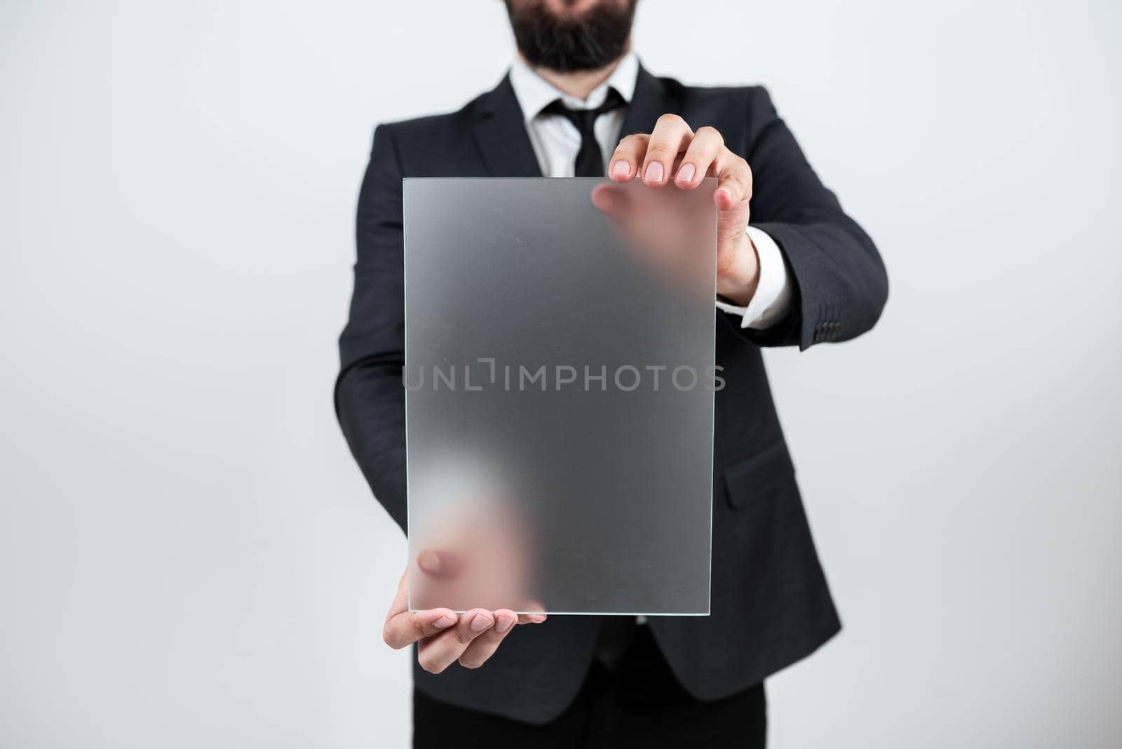 Male Professional Holding Blank Placard And Displaying Business Data. Businessman Wearing Suit Showing Rectangular Board For Marketing And Advertising The Company. by nialowwa