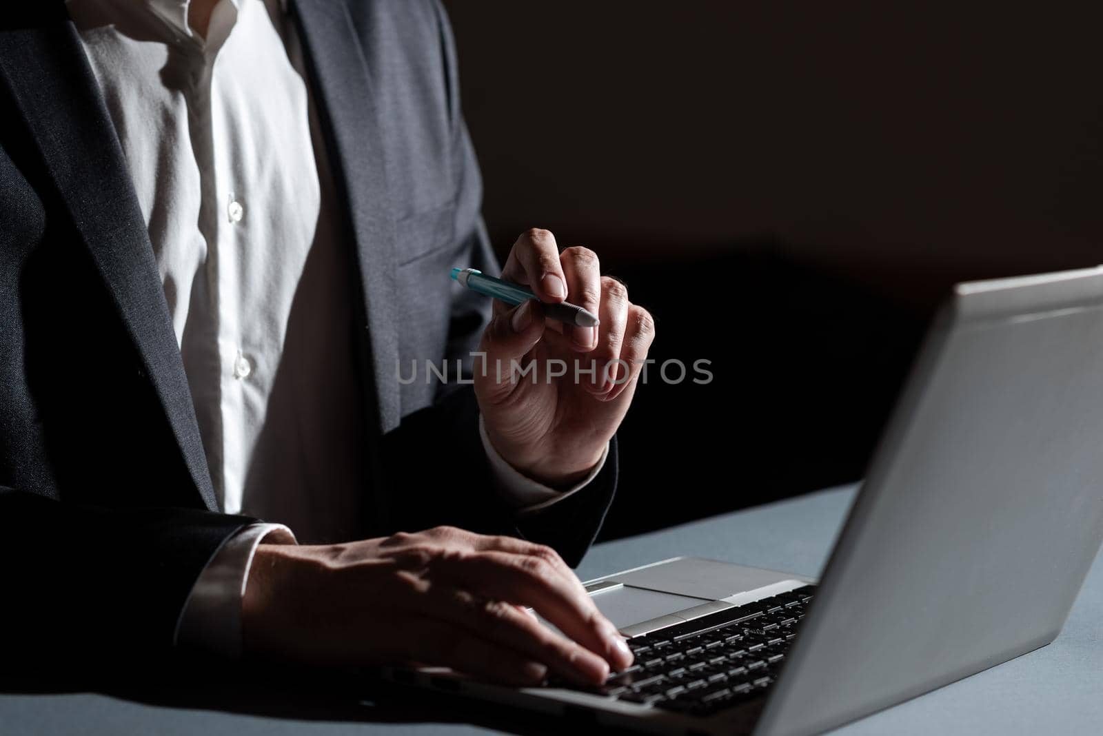 Businessman Typing Important Concept Into Lap Top And Pointing New Idea With Pen. Man In Suit Writing Crutial Messages On Computer Keyboard. Executive Presenting Late Data. by nialowwa