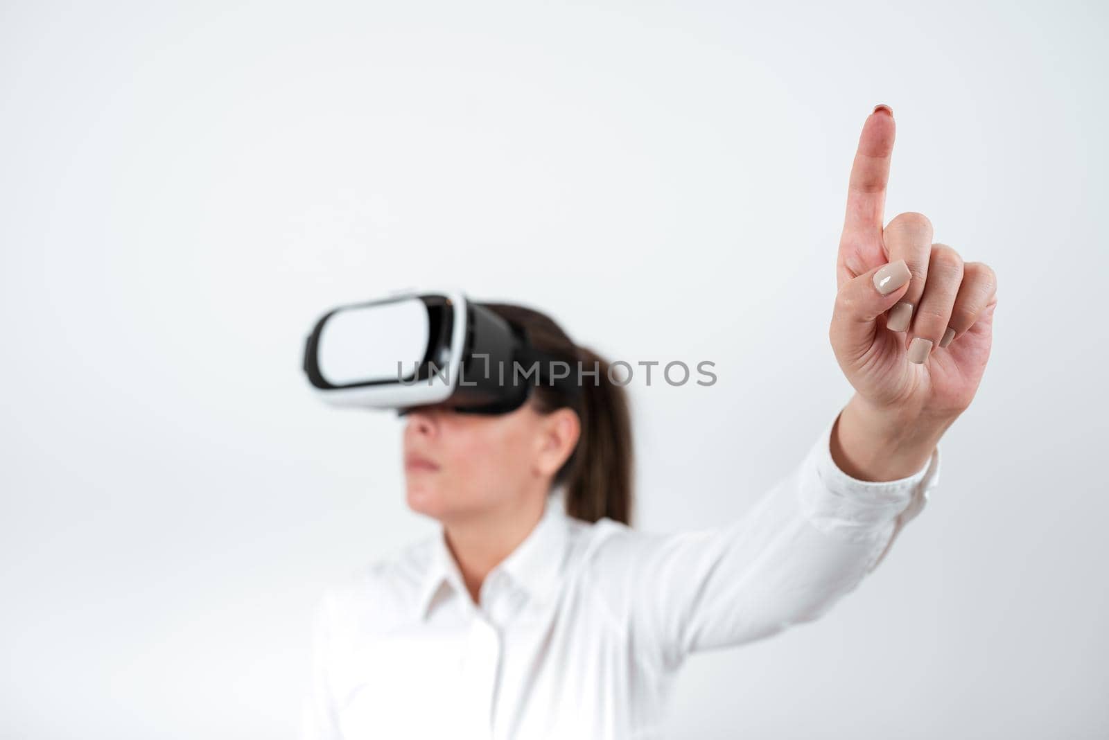 Woman Wearing Vr Glasses And Pointing On Important Messages With One Finger. Businesswoman Having Virtual Reality Eyeglasses And Showing Crutial Informations. by nialowwa