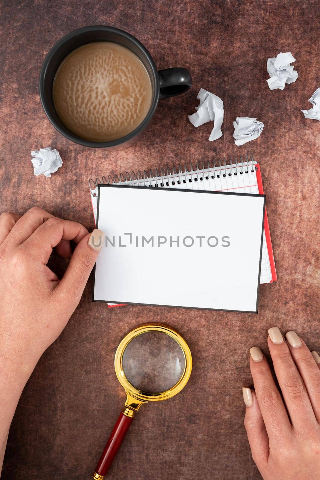 Hands Of Woman Having Blank Sheet With Copy Space, Magnifying Glass, Coffee Cup And Crumpled Papers Over Wooden Table. Businesswoman Showing New Ideas And Strategies. by nialowwa