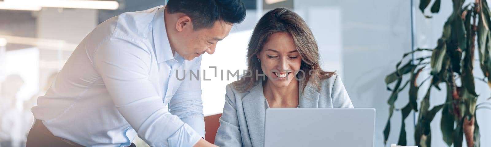 Confident asian office worker discussing work with mature female business woman. Blurred background