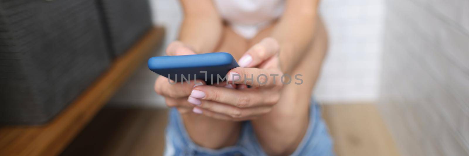 Close-up of woman texting sitting on toilet, visit restroom with mobile phone, female read news on smartphone. Bathroom, nature calls, social media concept