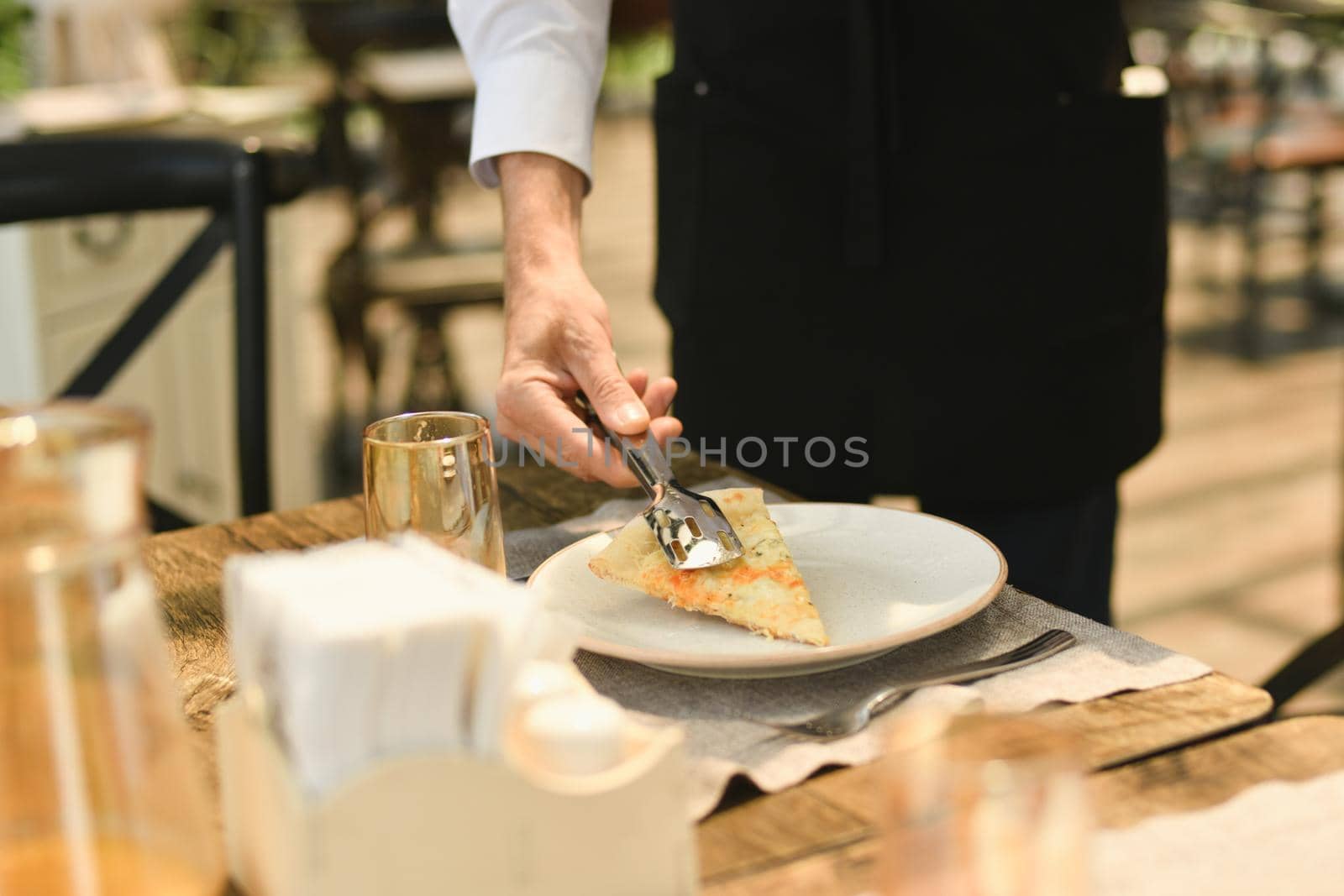 The waiter punishes a piece of cheese on a plate in a restaurant.