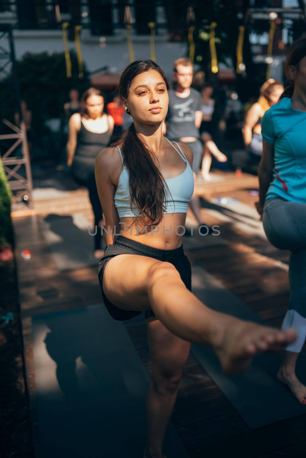 A woman does yoga together with her group in the open air by teksomolika