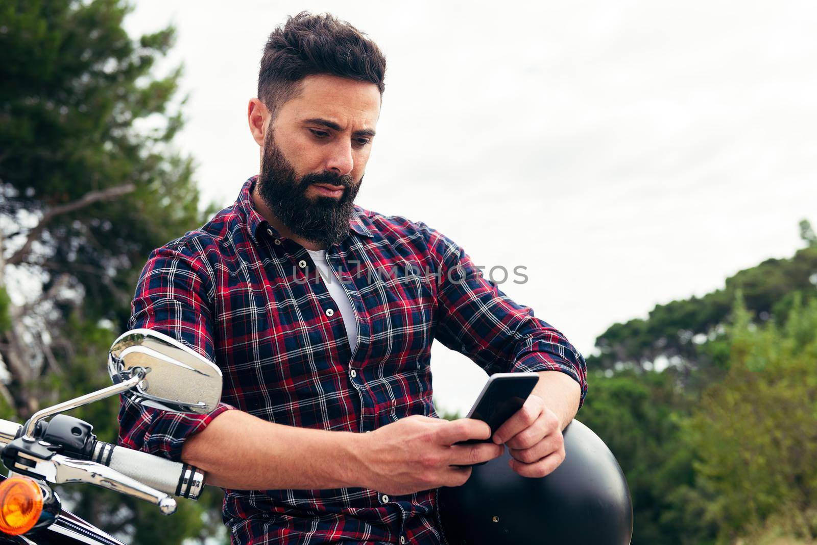 man consulting the phone sitting on a motorcycle by raulmelldo