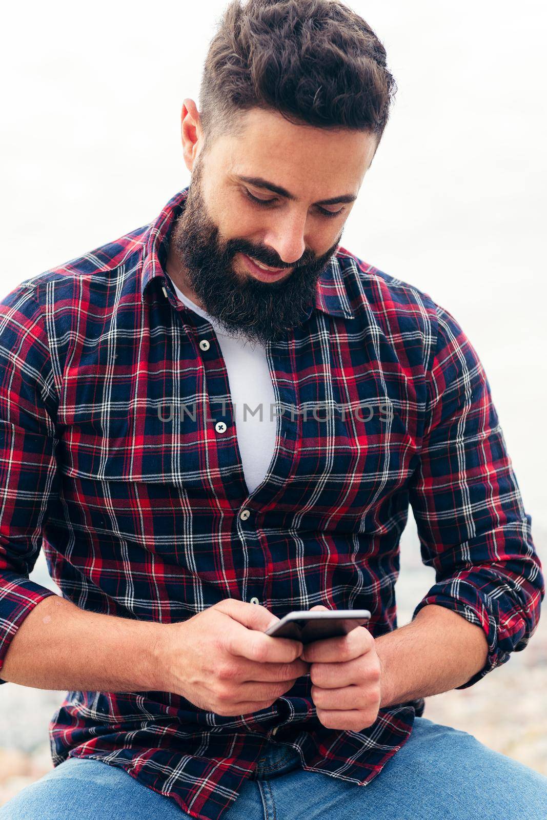 bearded man typing a text message on his phone by raulmelldo