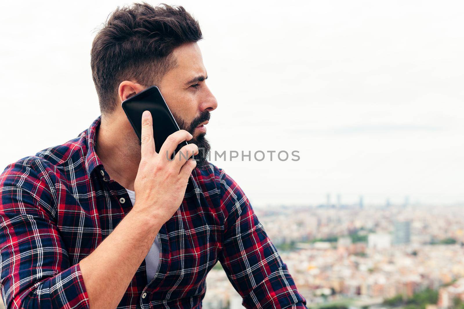 portrait of a handsome bearded man talking by mobile phone outdoors, concept of freedom and technology, copy space for text