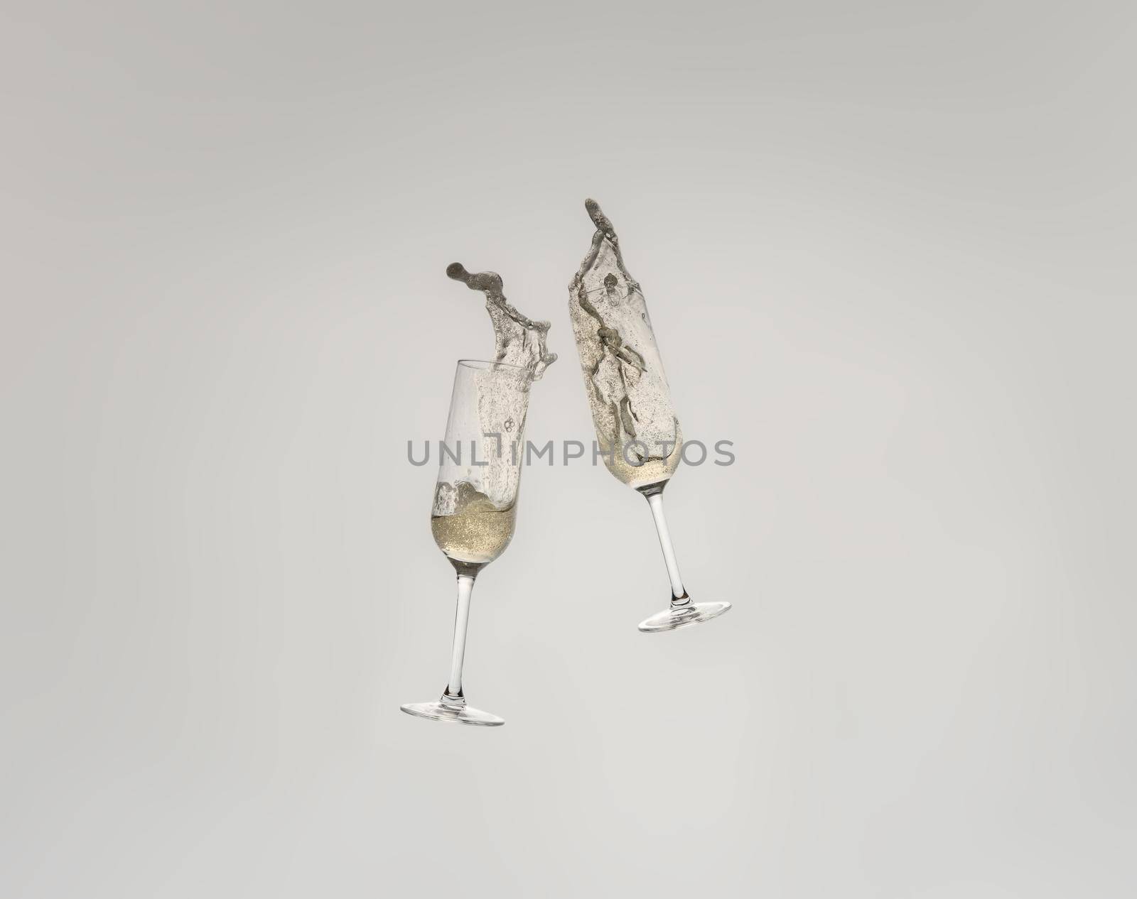 Splash of two crystal glasses toasting with champagne for a celebration. Splash on white cut-out background. graphic resource.