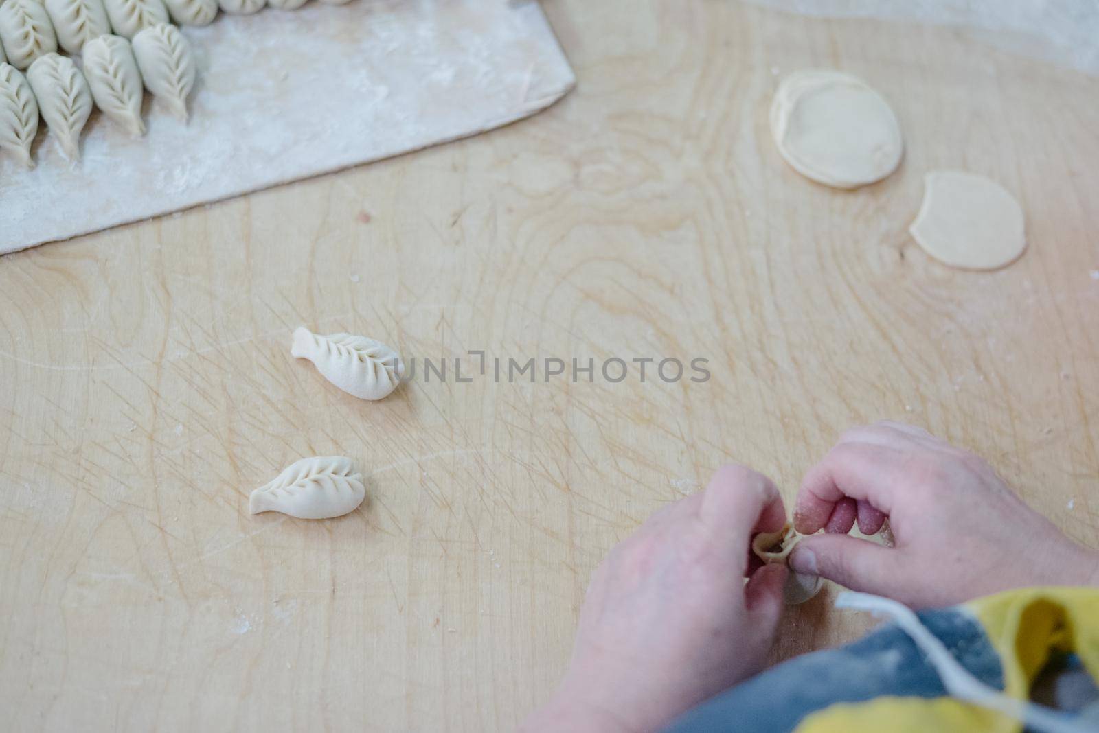 Front view of woman's hands making meat dumpling. The process of making homemade dumplings. Minced meat on dough, the process of cooking italian ravioli. Russian food.