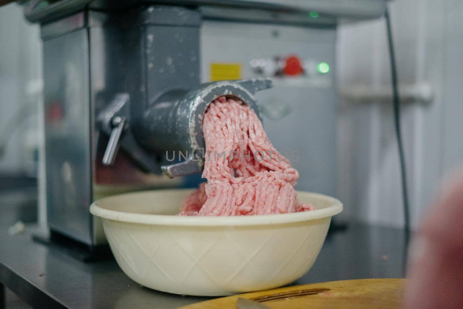 Close up of front part of meat grinder or mincing-machine with mincemeat in. Showing the forcemeat process.