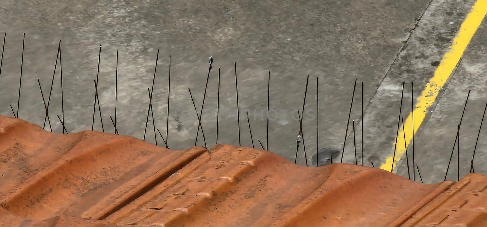 Close-up of anti-bird steel poles on the tiled roof of a building to prevent birds from building the nest.