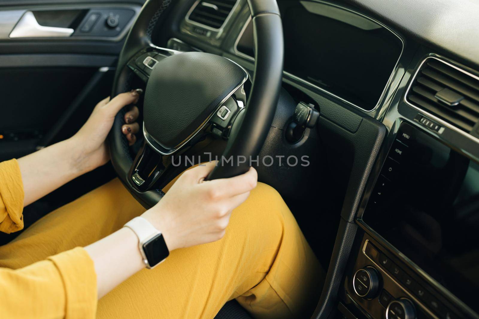 Woman hands holding a steering wheel confidently. Female hands with a clock on the steering wheel of a car while driving.