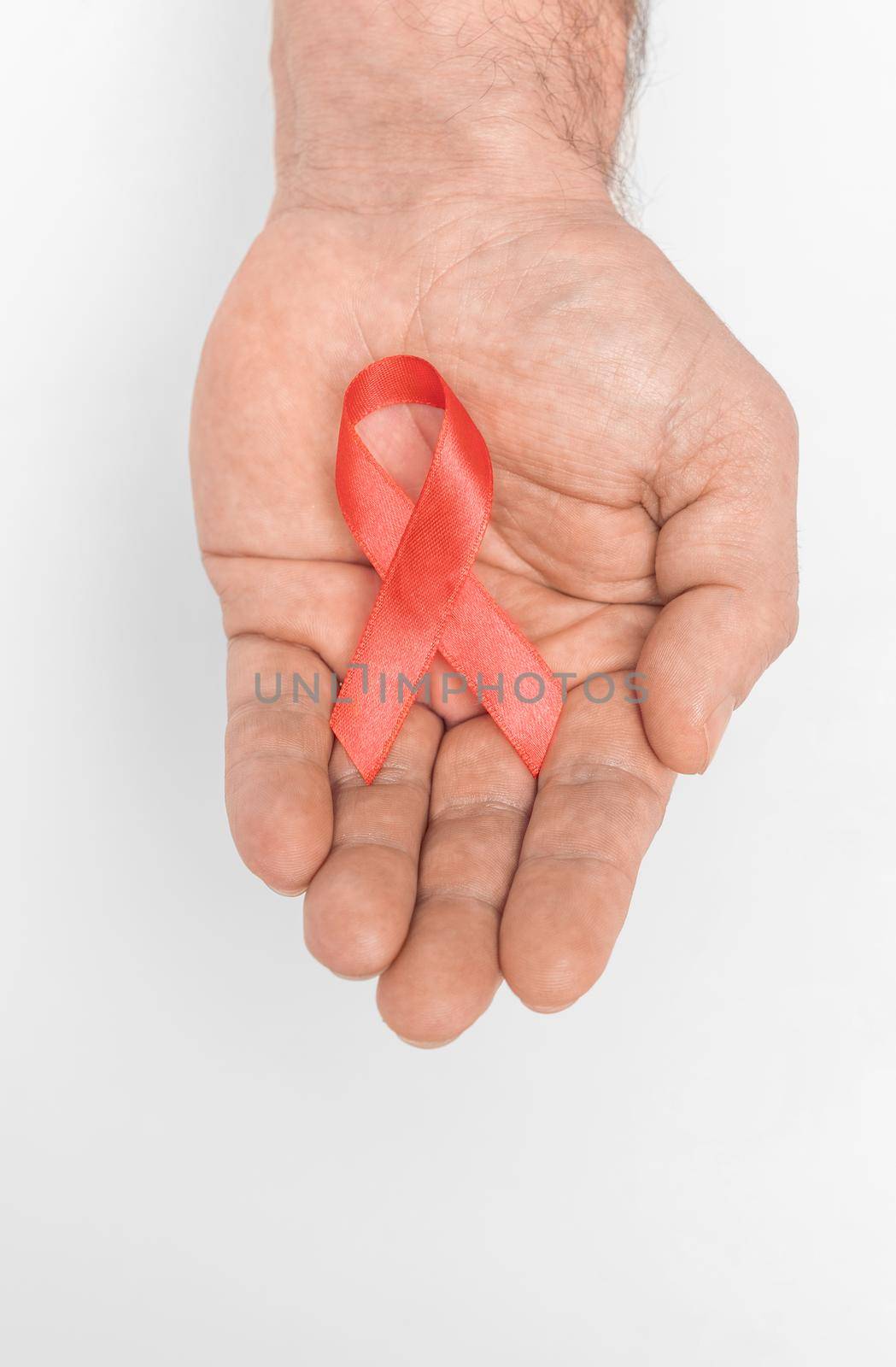 Red ribbon bow awareness on mans hand isolated on white background. HIV, AIDS world day. Social life issues concept. Aids charity fund concept. Healthcare and medicine concept.