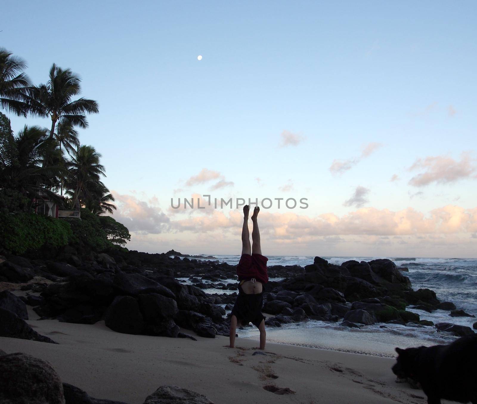 Man Handstanding on beach at dawn as wave crash on the North Shore by EricGBVD