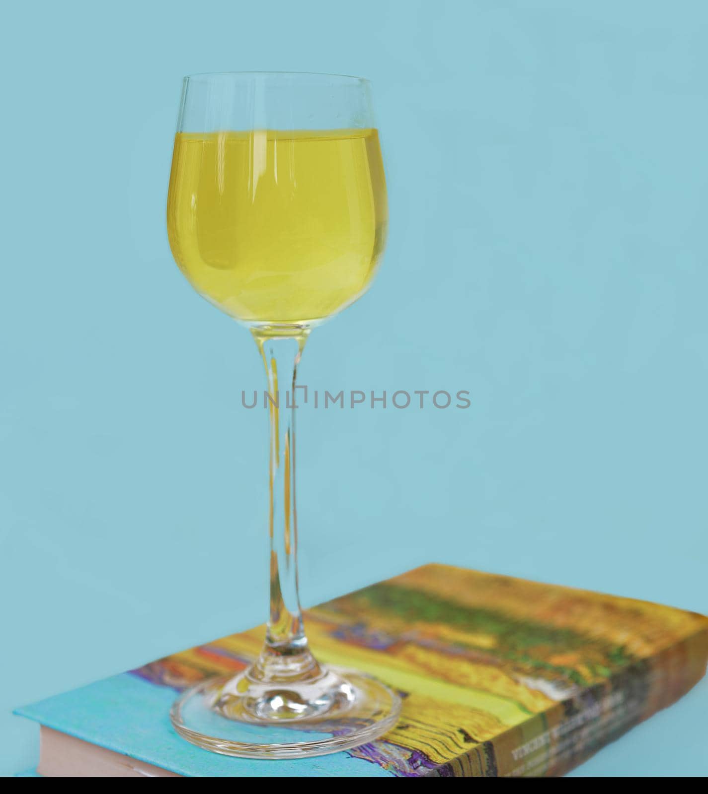 Limoncello in glass, sweet Italian lemon liqueur, traditional strong alcoholic drink and lemons on a blue background.