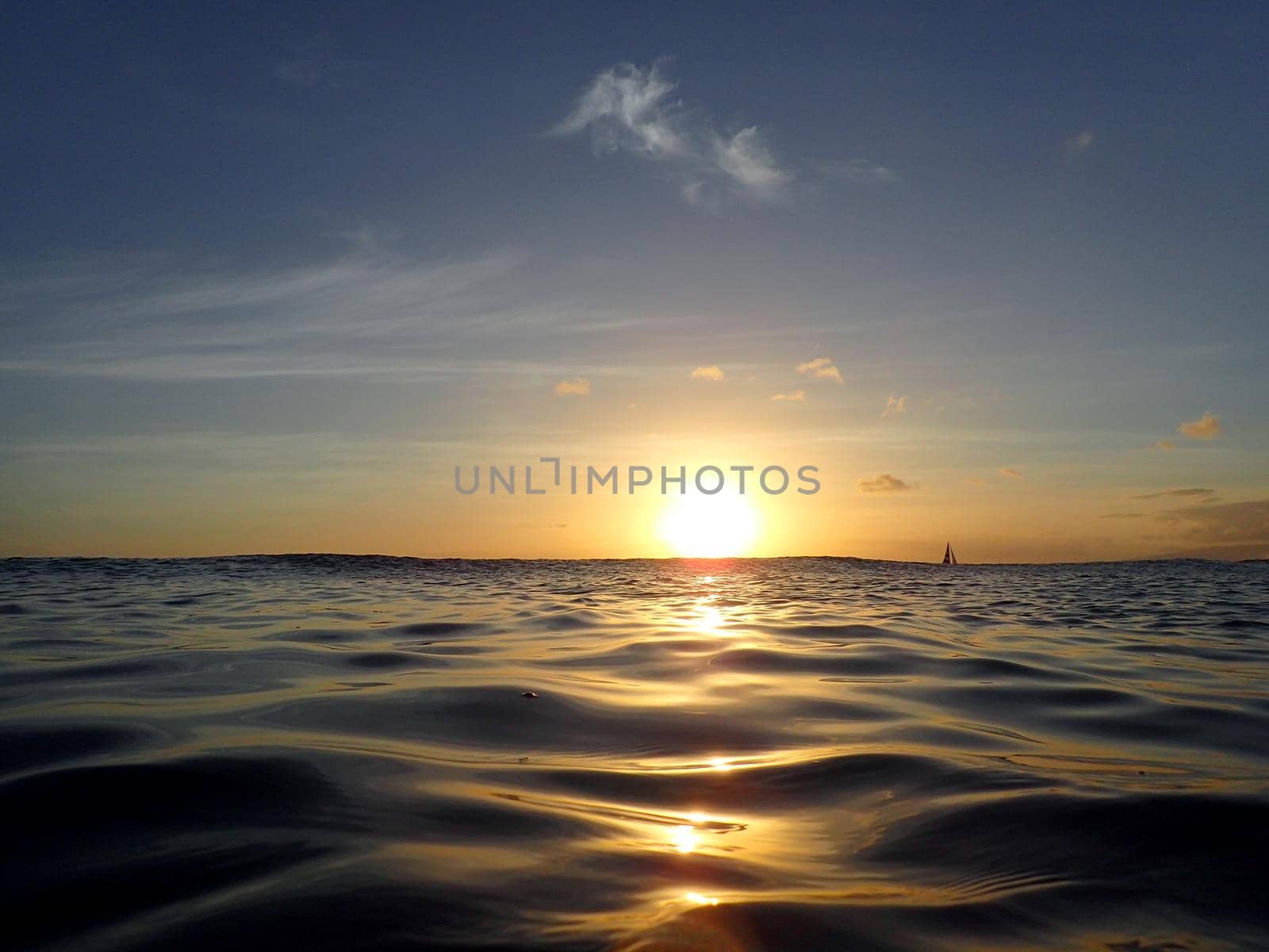 Dramatic lighting the sky and ocean during sunsets with light reflecting on ocean waves moving with boats on the water in the distance off Waikiki with clouds on Oahu, Hawaii.