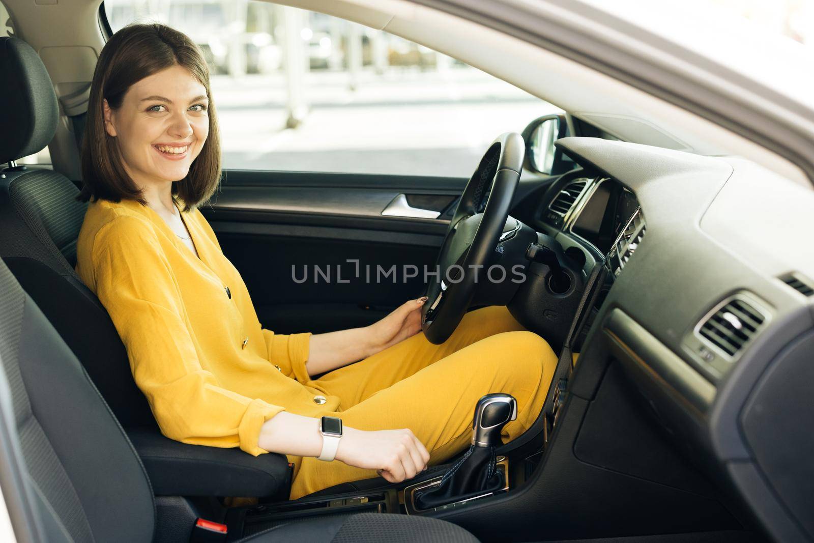 Smiling young woman enjoying driving on a beautiful sunny day. Pretty adorable female riding car smiling outside city street by uflypro