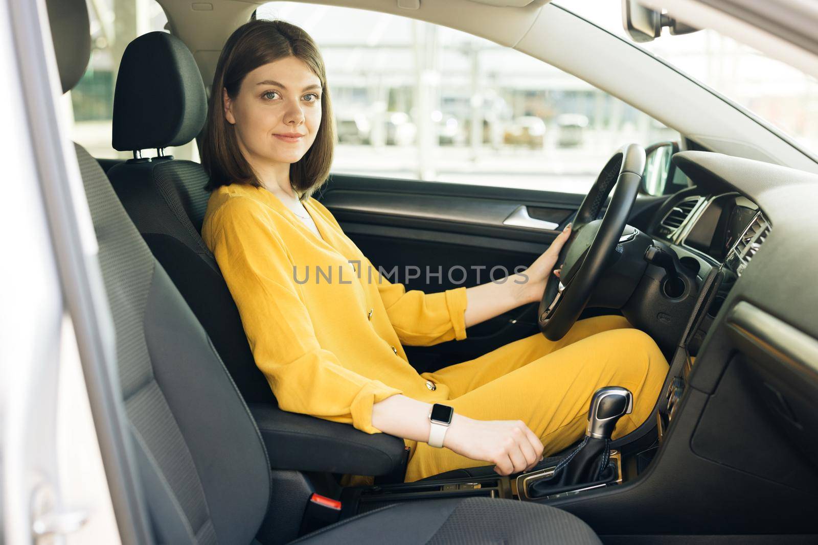 Woman driver driving a car. Safety and people concept. Young female driver driving car in city. Portrait of girl fasten seat belt in her car. Protection of person in vehicles.