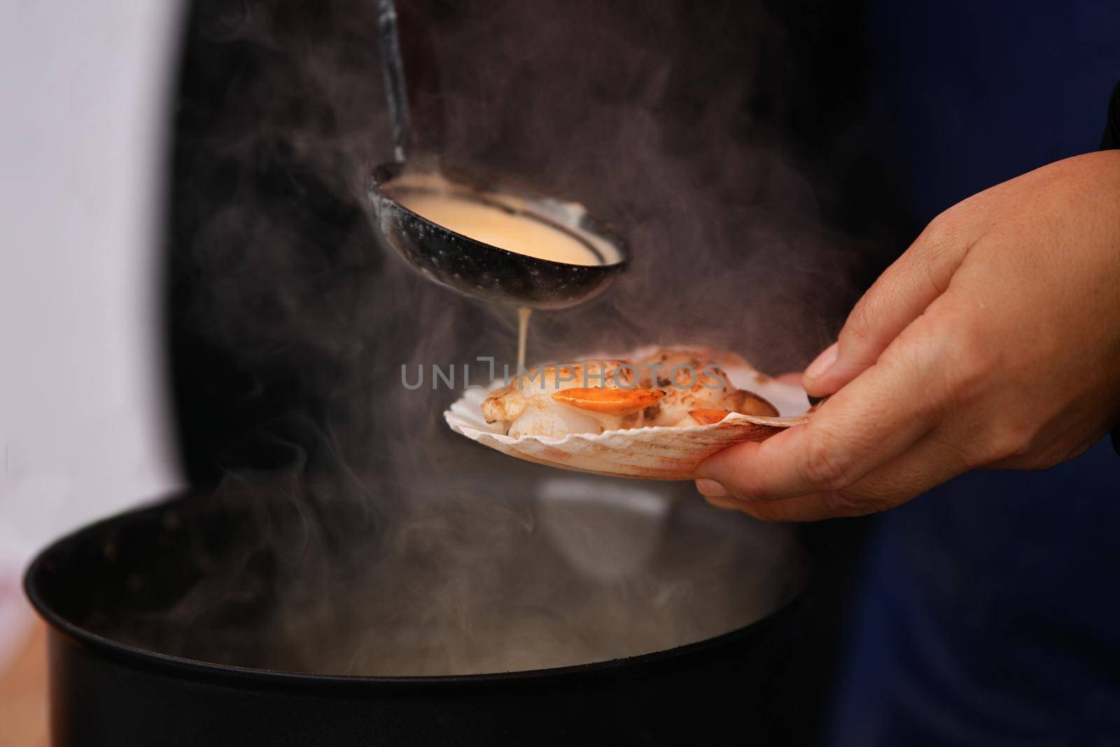 The seller pours white sauce on the scallops