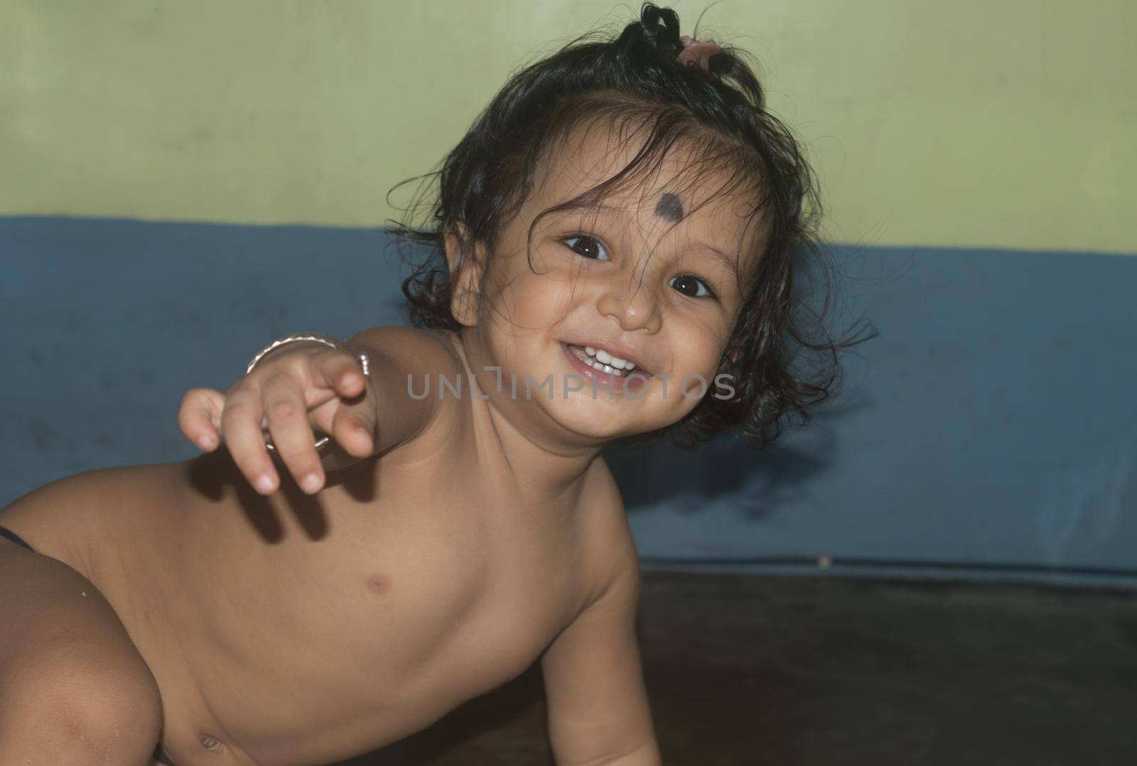 Cute happy indian baby without shirt crawling smiling and looking at camera. by sudiptabhowmick
