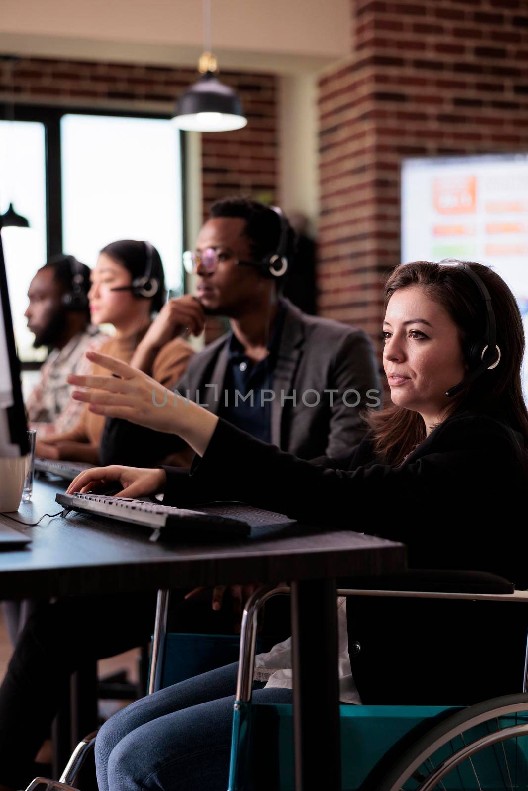 Woman living with disability answering client call at customer service, wheelchair user with physical health condition working at helpline support. Helpdesk operator with chronic pain.