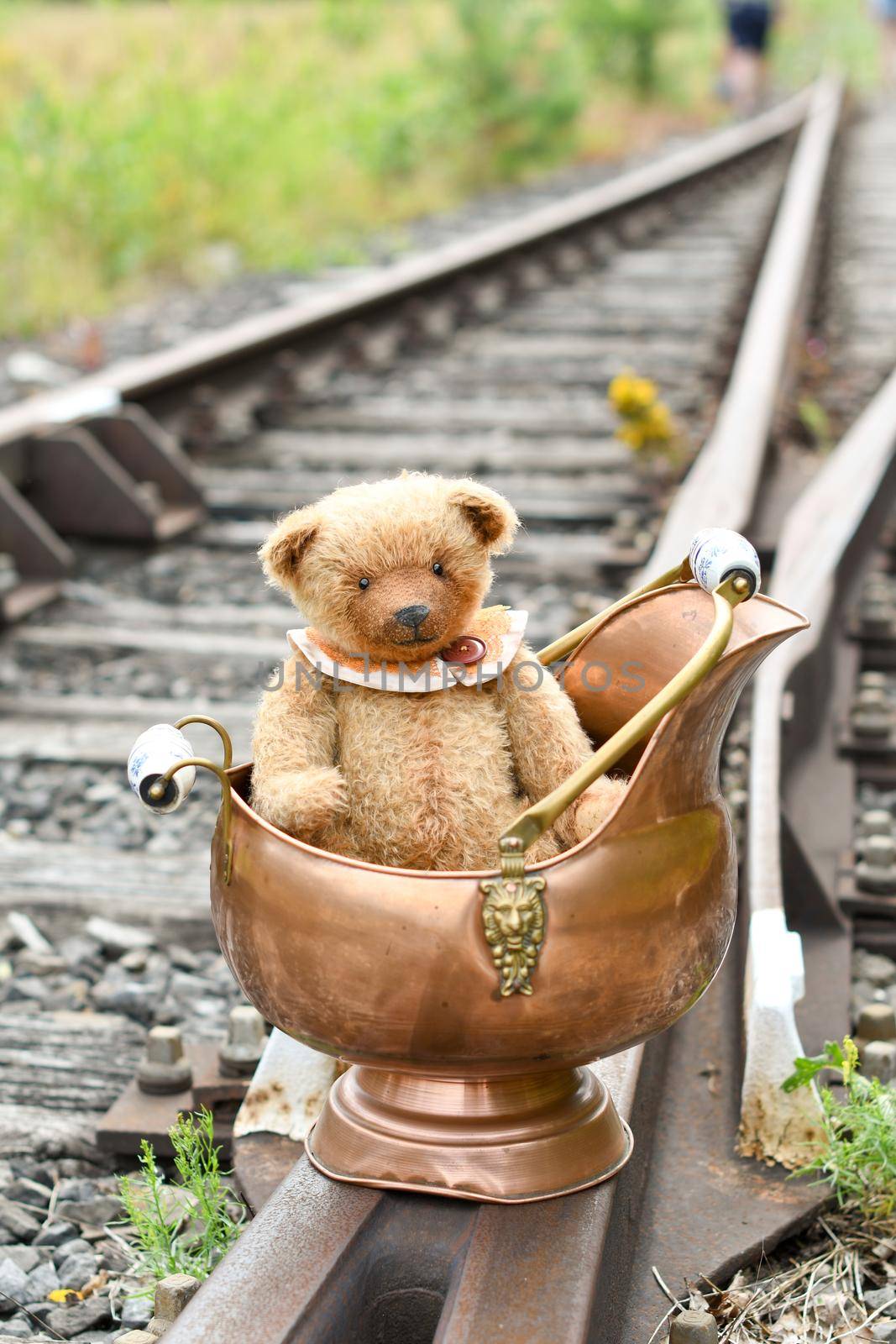 a cute brown teddy bear sits alone on empty mini-rails and looks into the distance, do-it-yourself toy. High quality photo