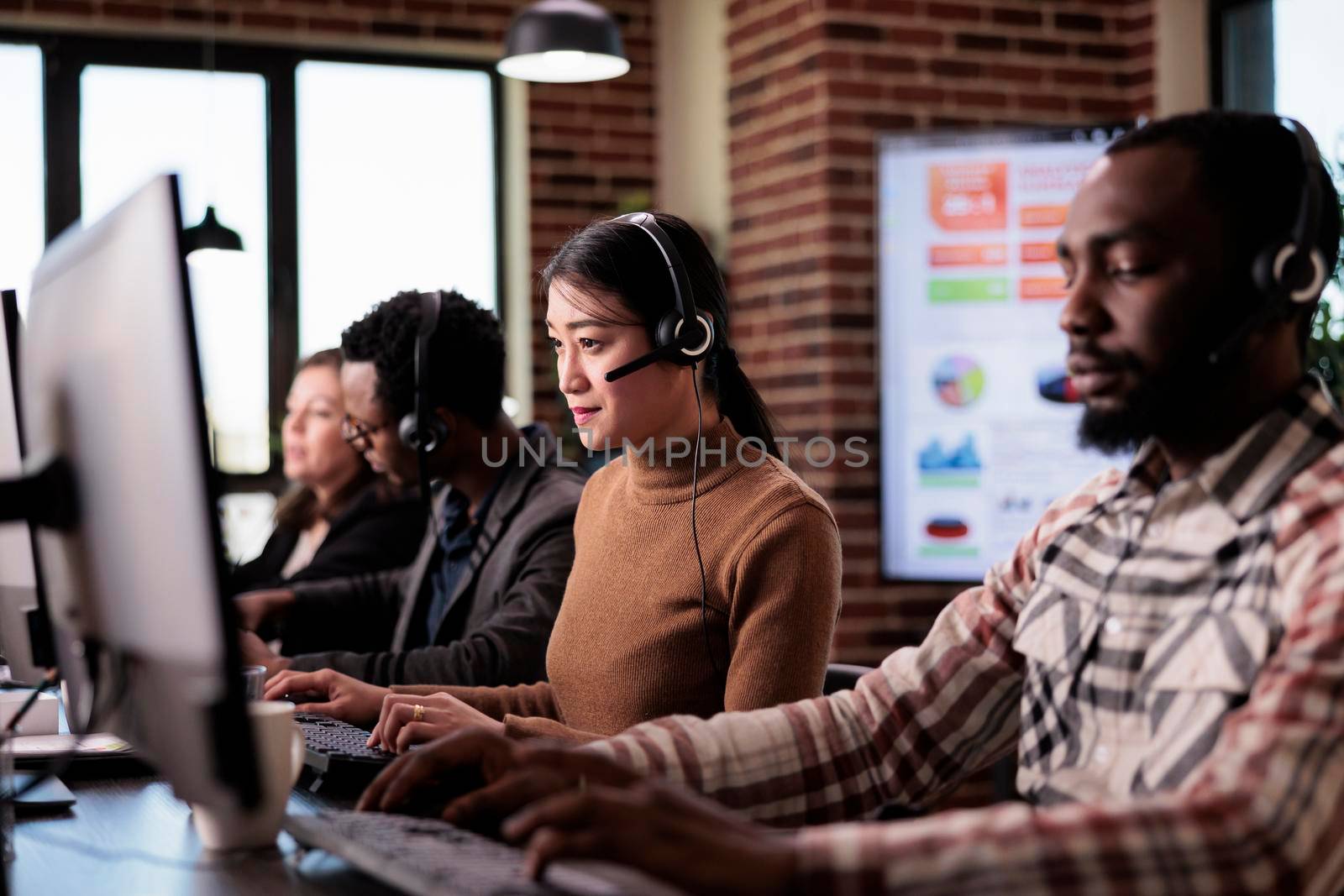 Asian operator working as sales assistant at call center service, helping clients at customer care support. Telecommunication consultant using telemarketing helpline at reception desk.