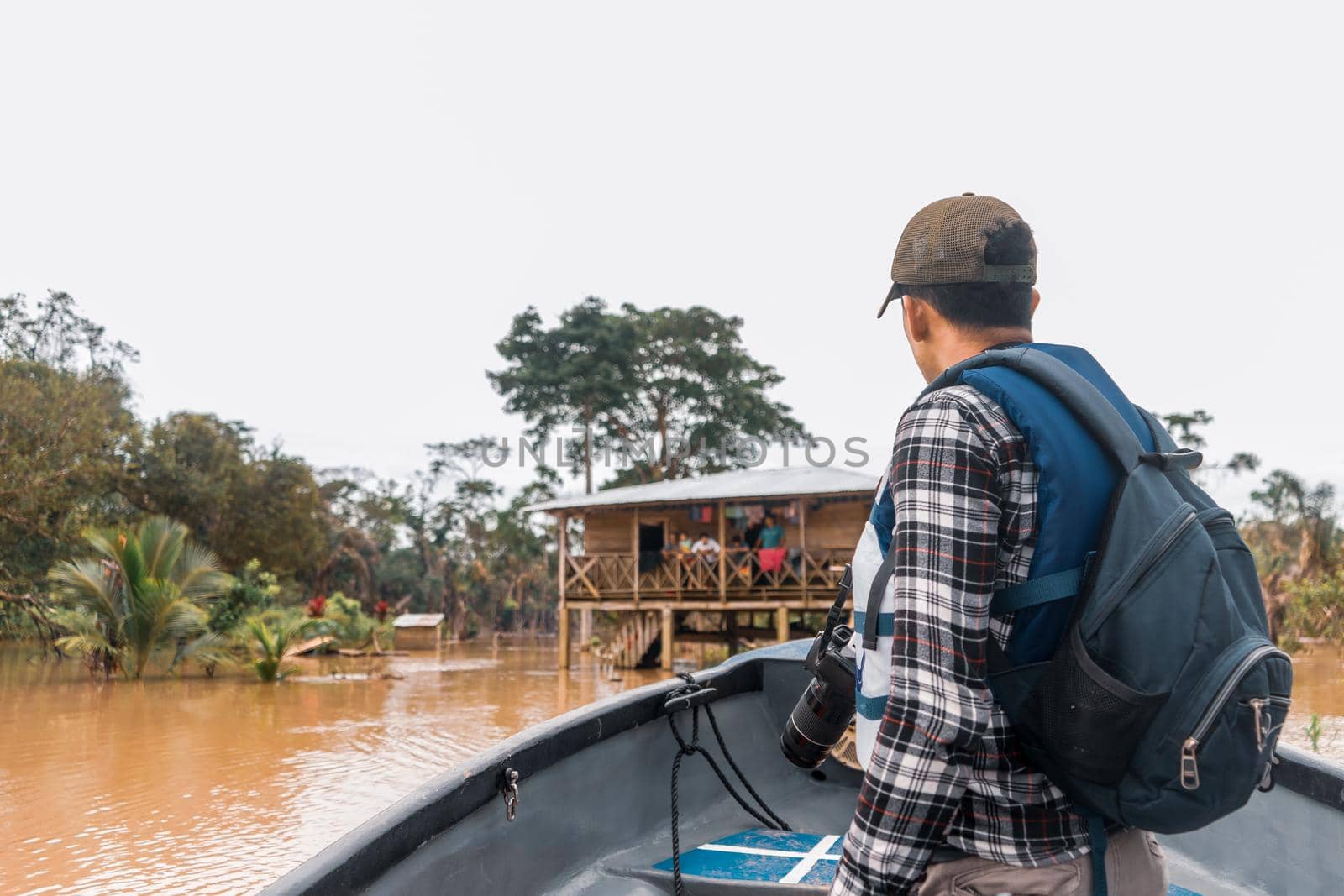 Latino man sailing a boat down a muddy river and visiting an indigenous community in El Rama, Nicaragua
