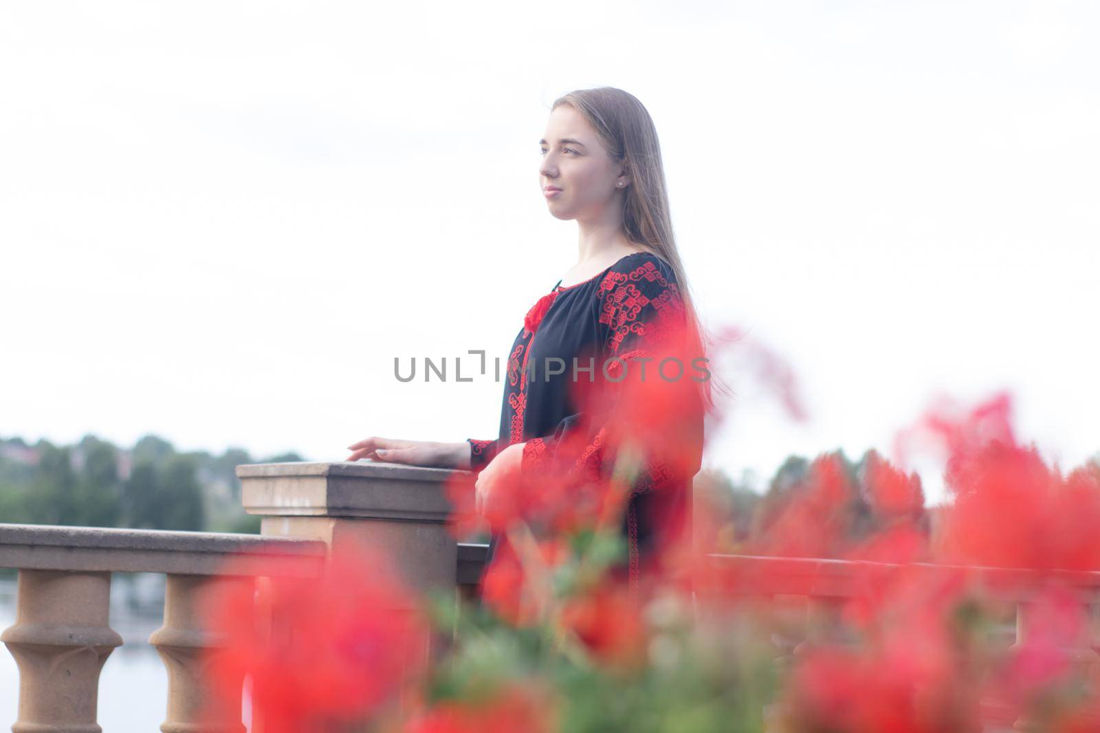 girl in national traditional ukrainian clothes. black and red embroidered dress. woman model posing in park outdoors.