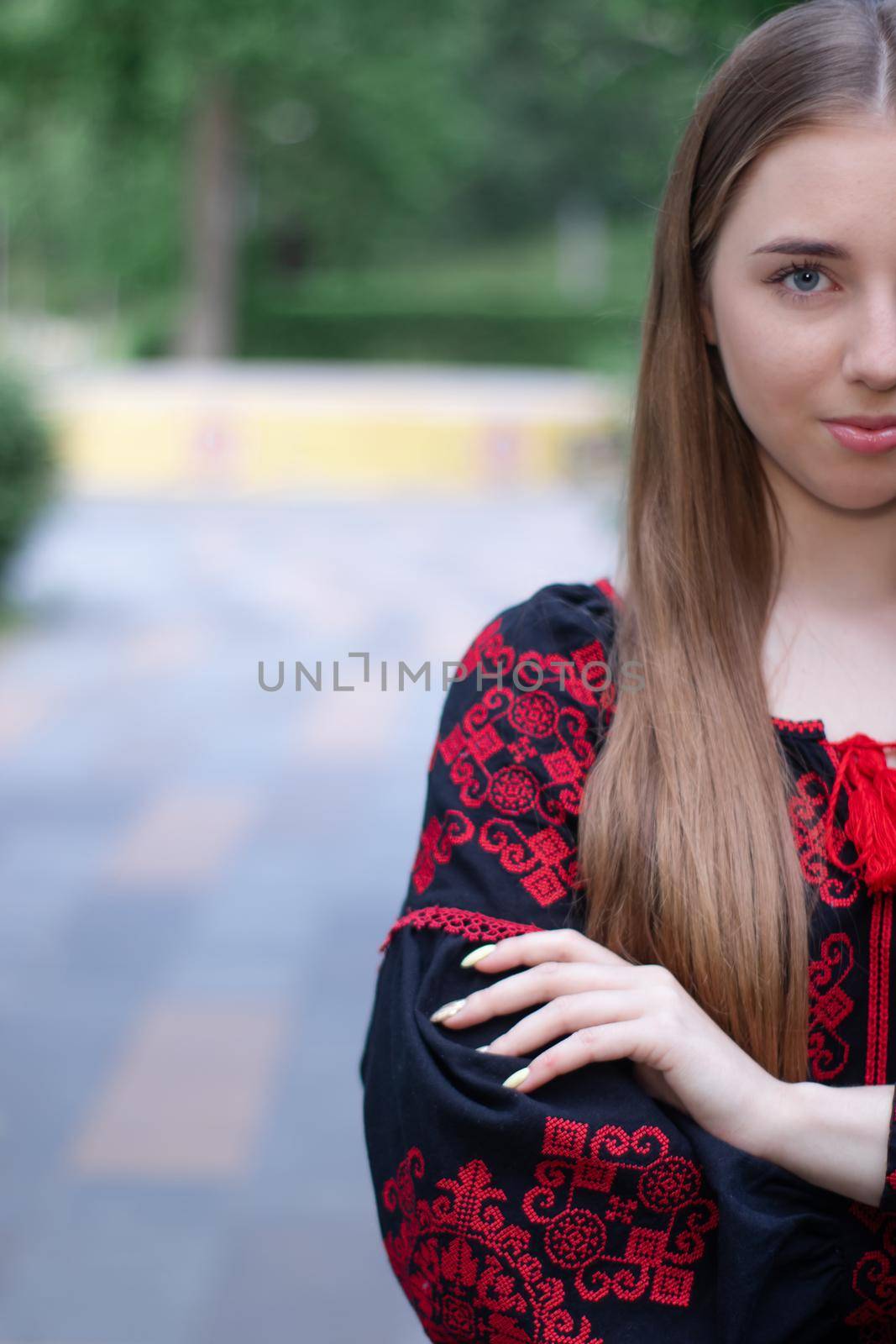 girl in national traditional ukrainian clothes. black and red embroidered dress. woman model posing in park outdoors.