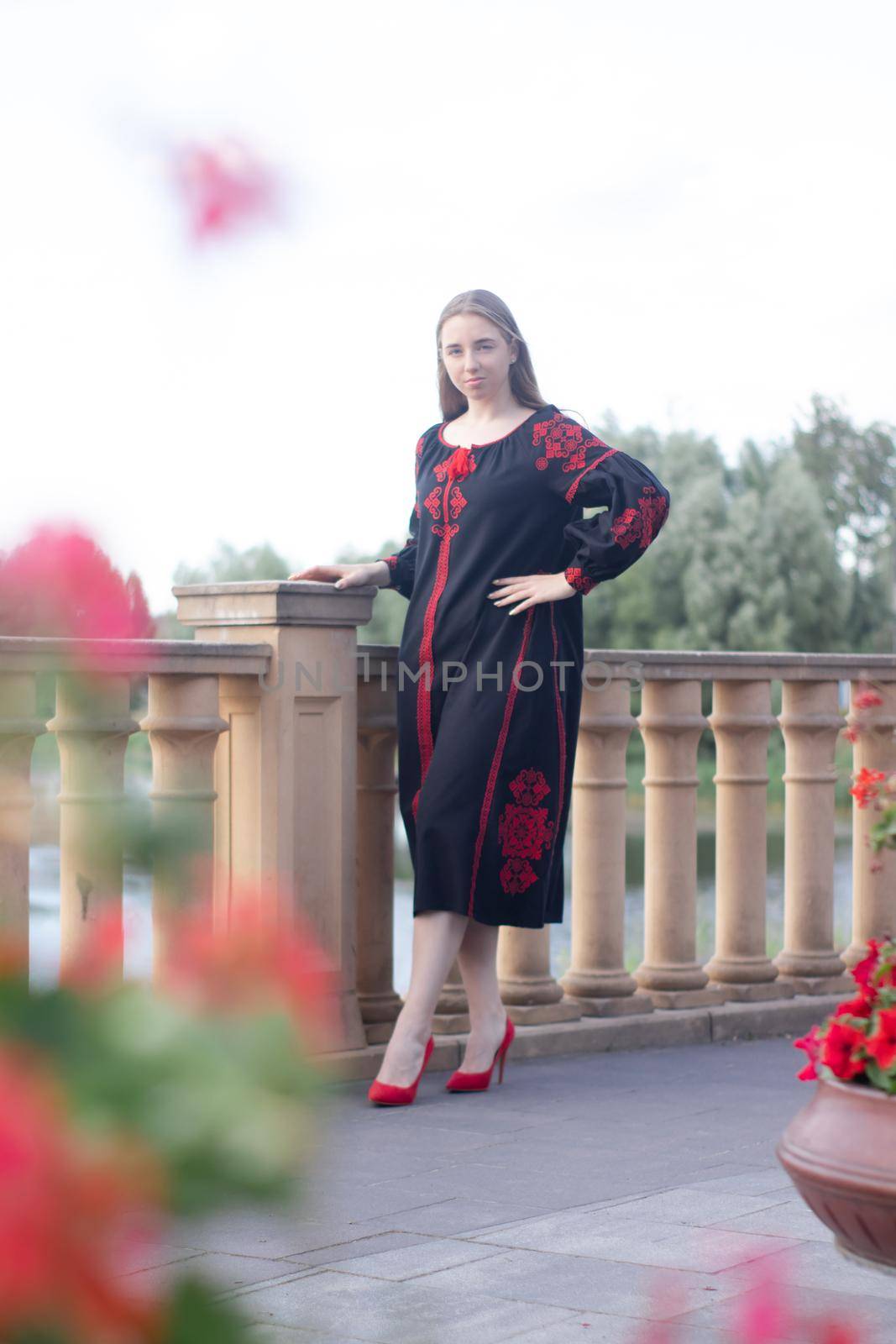 girl in national traditional ukrainian clothes. black and red embroidered dress. woman model posing in park outdoors.