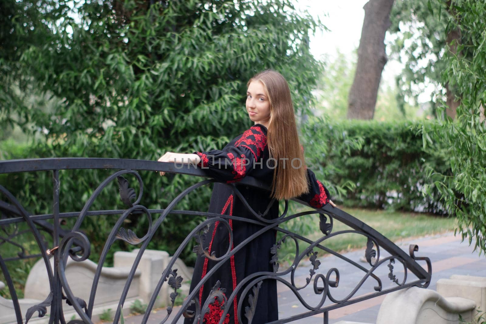 girl in national traditional ukrainian clothes. black and red embroidered dress. woman model posing in park outdoors.