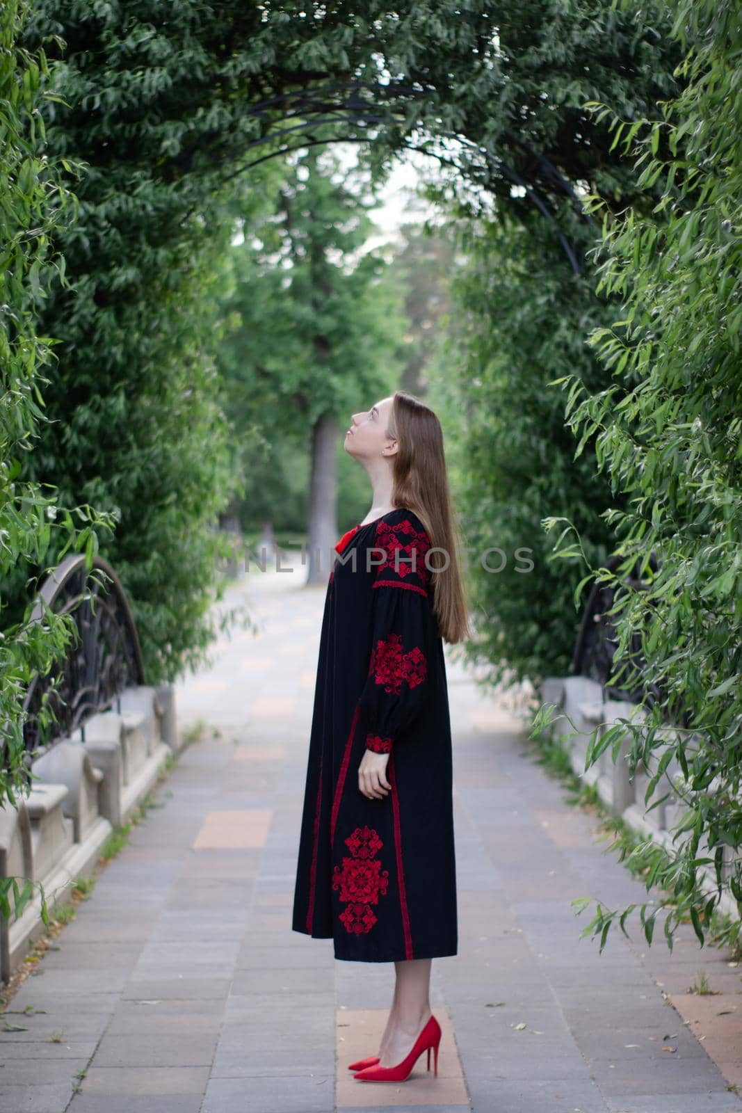 girl in national traditional ukrainian clothes. black and red embroidered dress. woman model posing in park outdoors.